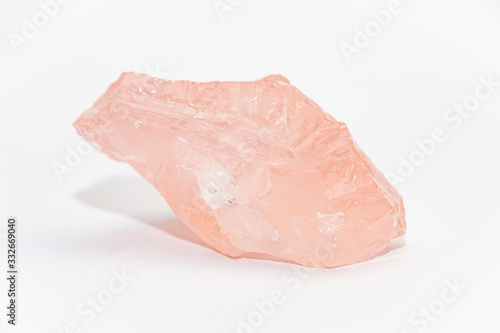 Big piece of rose quartz SiO2 unpolished with uneven shiny surfaces on white background