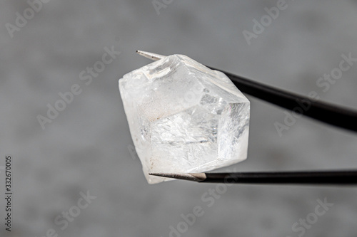 Konstfotografi Raw diamond big dob held by tweezers in front of grey surface