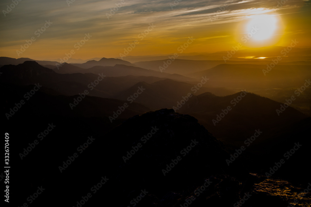 Dark silhouettes of the Carpathian rocky mountains and sunset sky with a large yellow sun Dark silhouettes of the Carpathian rocky mountains and sunset sky with a large yellow sun
