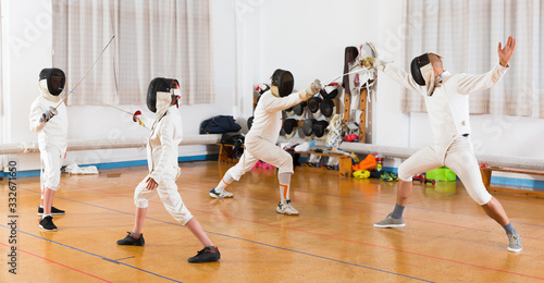 Kids and adults practicing fencing techniques