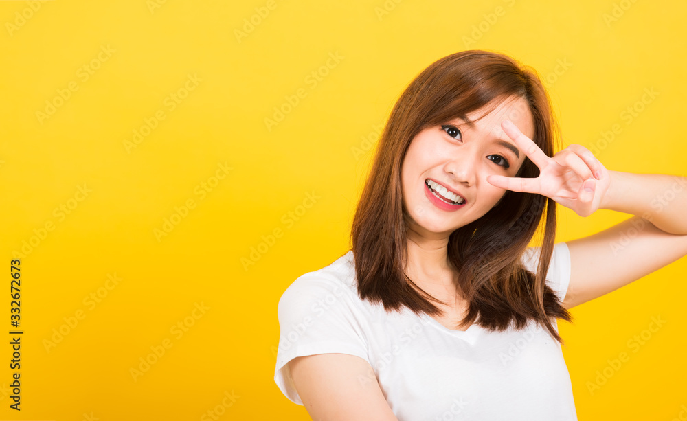 woman teen smile standing wear t-shirt showing finger making v-sign symbol near eye woman teen smile standing wear t-shirt showing finger making v-sign symbol near eye