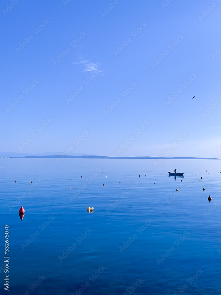 Blue sea and sky background, silhouette of lonely boat