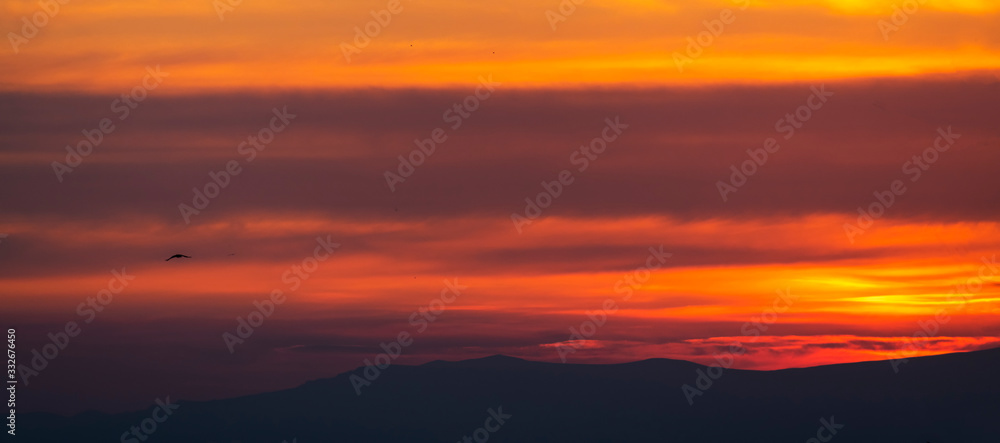 Mountains silhouettes, beautiful colorful dark sunset sky with orange clouds. Nature sky background.