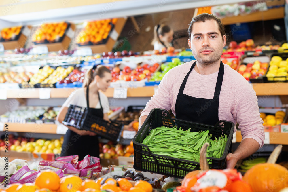 Young man with box of beans and woman wearing apron on background on the supermarket