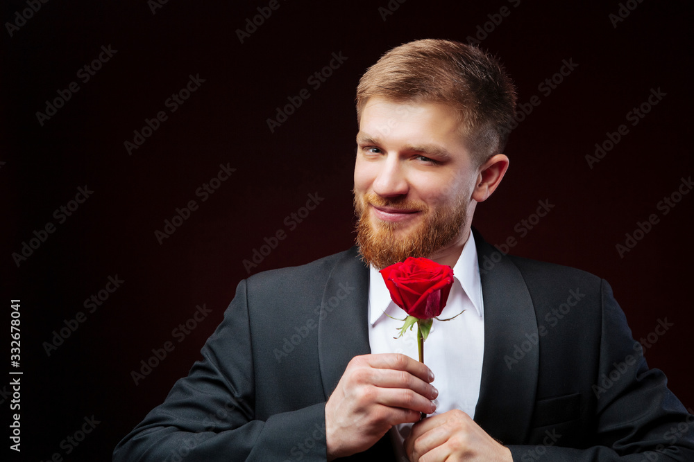 Close up of handsome boyfriend holding red rose. Bearded man is ready for 8th of March. Close up of handsome boyfriend holding red rose. Bearded man is ready for 8th of March.