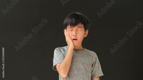 4k young Asian boy has teethache photo