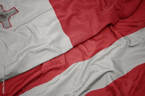 waving colorful flag of austria and national flag of malta.