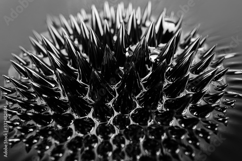 Ferrofluid, magnetic fluid close-up. Abstract minimalistic black trendy background. Fluid highly polarized in the presence of a magnetic field. Impressive, stylish iridescent black spikes. photo