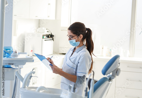 Female dentist in dental office .She tired after hard work  sitting on chair and planing list of exams for next working day. 