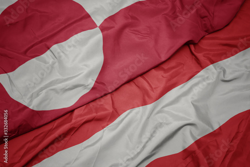 waving colorful flag of austria and national flag of greenland.