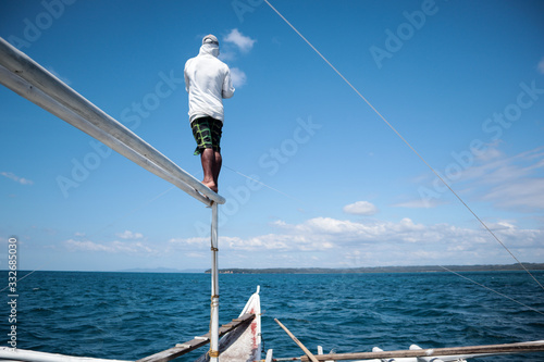 Man standing on a bamboo pole against a clear blue sky
