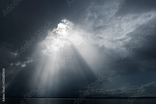 Ray Of Light Piercing The Clouds In The Sky / Storm Clearing Over The Water photo