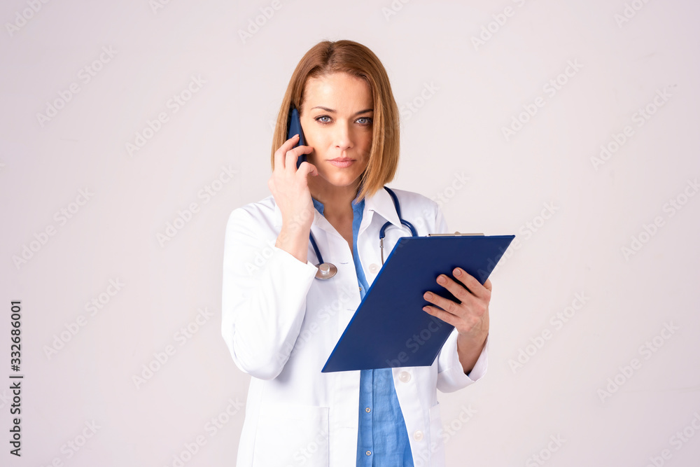 Middle aged female doctor making a call while standing at isolated background Middle aged female doctor making a call while standing at isolated background