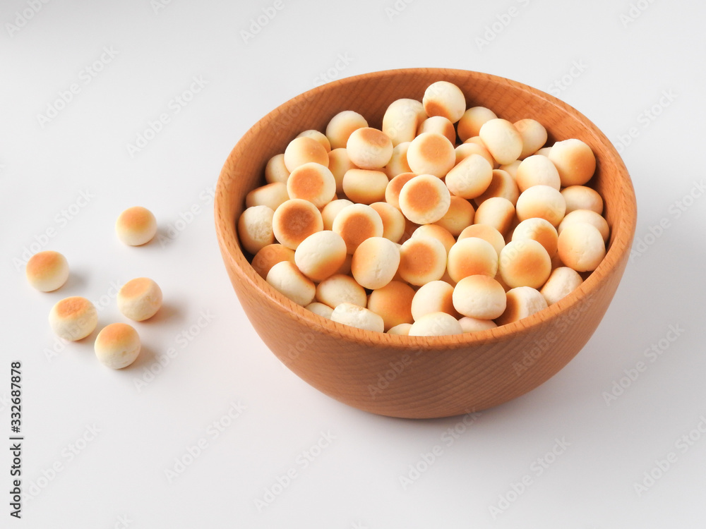 High angle view of little ball cookies on wooden bowl isolated on white background. Designed mouthpieces for children, which is melted into the mouth to make it easier for children to digest. High angle view of little ball cookies on wooden bowl isolated on white background. Designed mouthpieces for children, which is melted into the mouth to make it easier for children to digest.