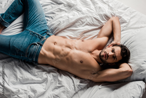 top view of handsome shirtless sexy man lying on bed isolated on grey
