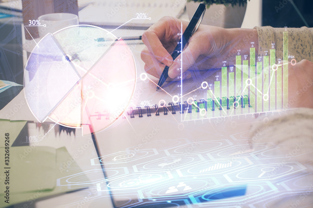 Hand taking notes in notepad. Forex chart holograms in front. Concept of research. Double exposure Hand taking notes in notepad. Forex chart holograms in front. Concept of research. Double exposure