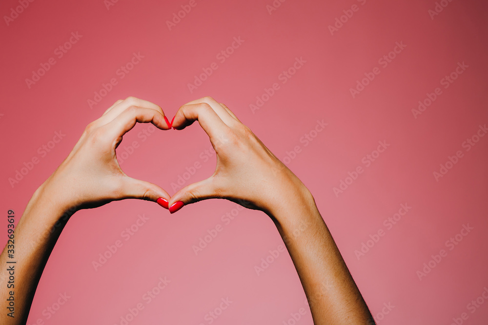 Woman's hands with bright manicure isolated on pink background love sign Woman's hands with bright manicure isolated on pink background love sign