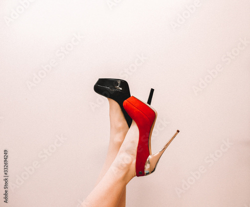 fashionable background for advertising shoes, red and black shoes on the foot in an unusual interesting position with a white background
