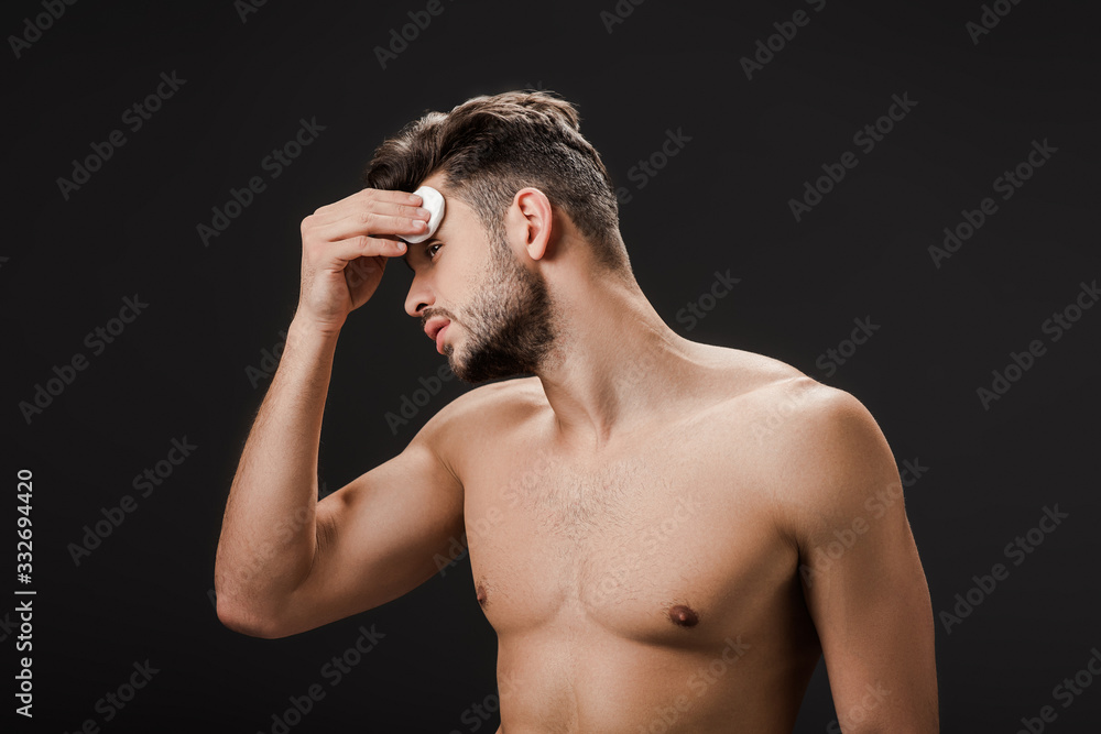 sexy naked man using cosmetic cotton pad isolated on black