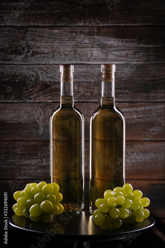Two white wine bottles on a table with wooden background