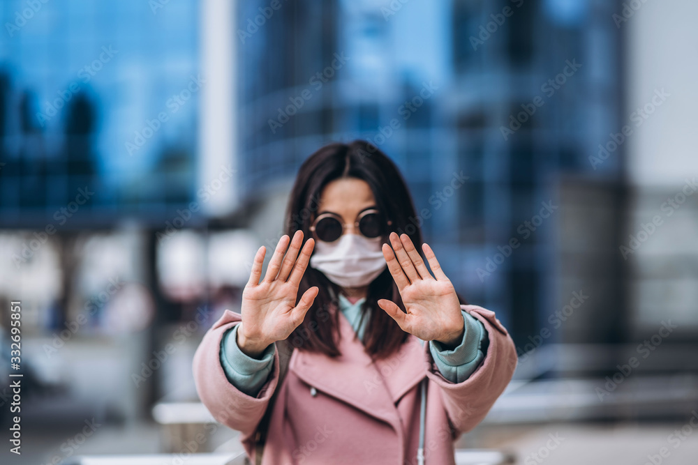 Female in medical mask outdoors show stop sign by her hands for social safe distance to prevent virus infection. Coronavirus, COVID-19, virus, desease, epidemic, pandemic, quarantine concept.