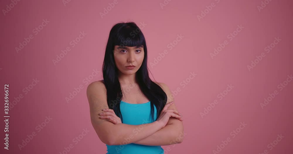 Offended brunette woman holding crossed arms and looking at the camera on pink background Offended brunette woman holding crossed arms and looking at the camera on pink background