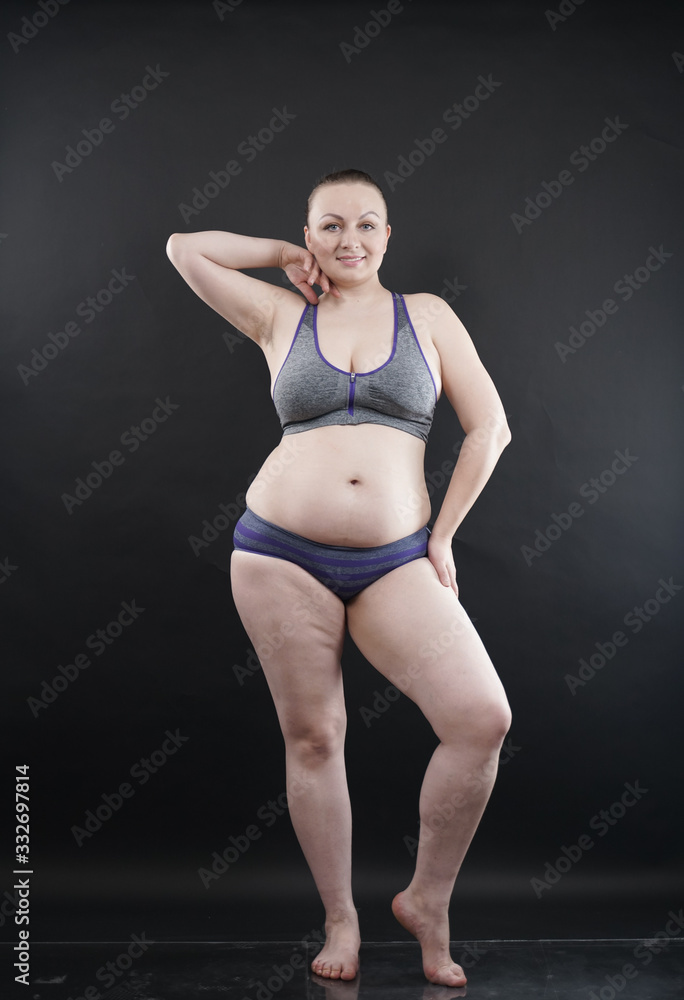 Obraz premium plus size woman shows her body in stretch marks and hair with cellulite and encourages you to love and accept yourself in any way . black background in the Studio. full- length photo.