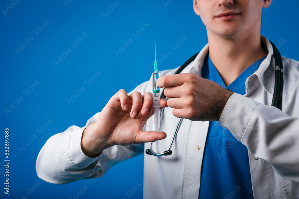 Clouseup of doctor with stethoscope preparing a syringe for injection isolated on blue background Clouseup of doctor with stethoscope preparing a syringe for injection isolated on blue background