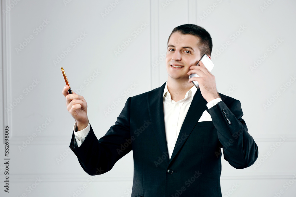 Portrait of a happy handsome businessman entrepreneur talking on phone holding the pen Portrait of a happy handsome businessman entrepreneur talking on phone holding the pen