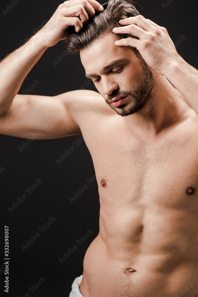 bearded handsome nude man combing hair isolated on black