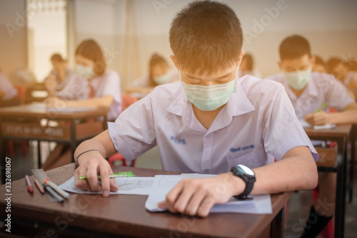 The Asian high school students in a white school uniform wearing the masks to do final exams in the midst of Coronavirus disease 2019 (COVID-19) epidemic and PM 2.5.