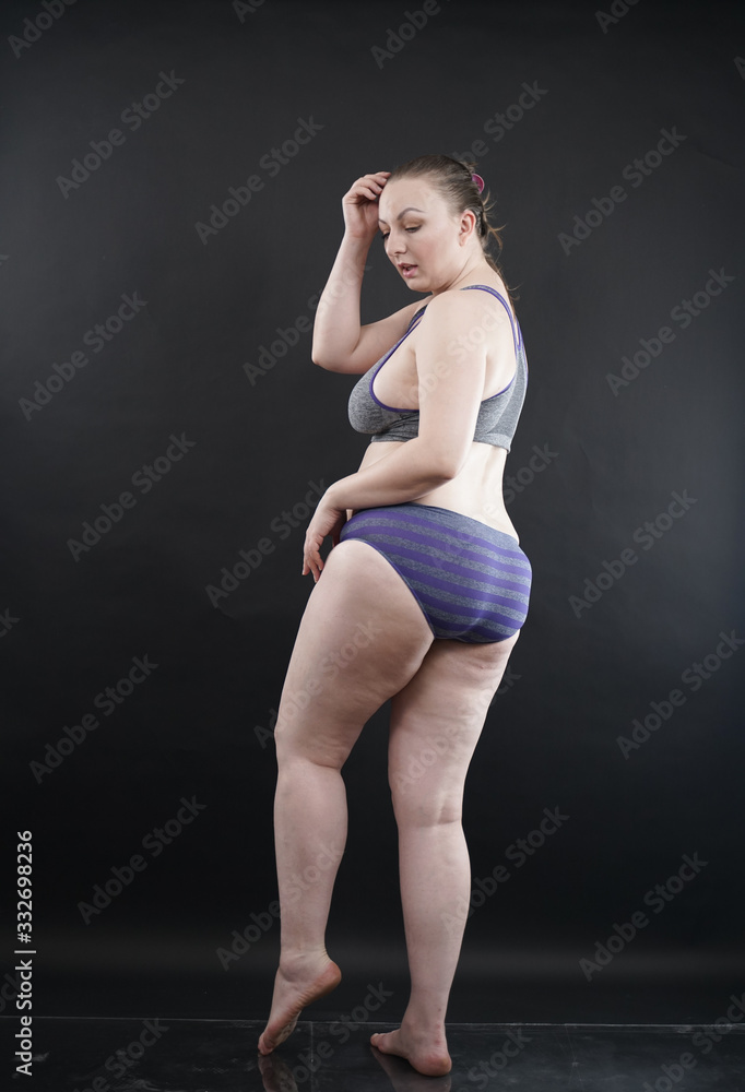 plus size woman shows her body in stretch marks and hair with cellulite and encourages you to love and accept yourself in any way . black background in the Studio. full- length photo. plus size woman shows her body in stretch marks and hair with cellulite and encourages you to love and accept yourself in any way . black background in the Studio. full- length photo.