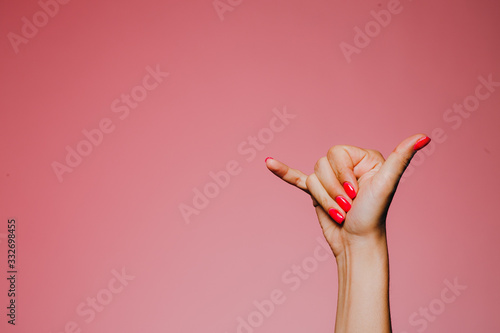 Woman's hands with bright manicure isolated on pink background call me sign