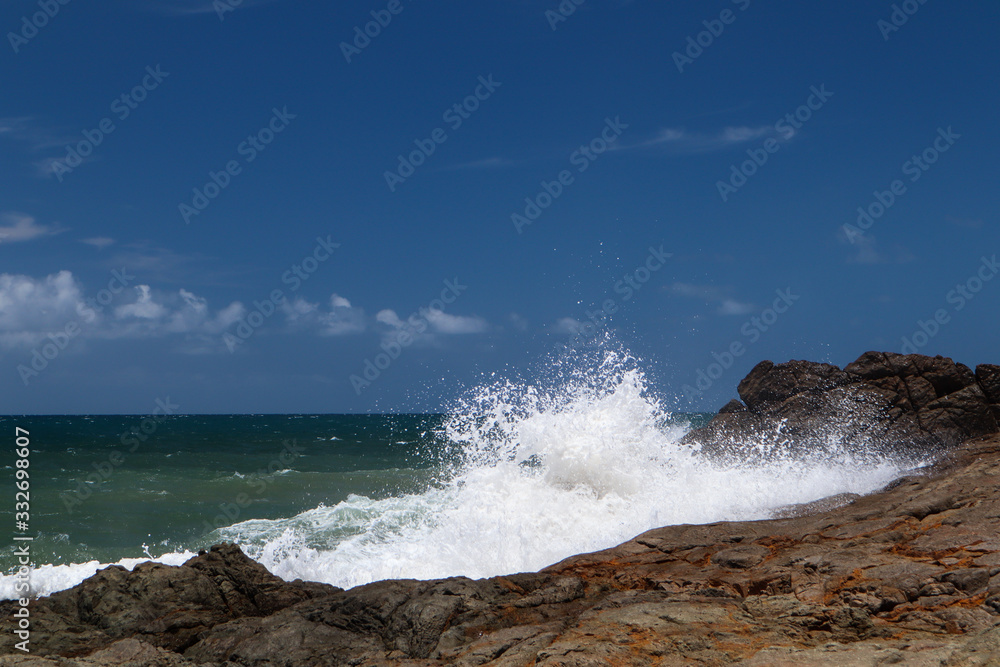 Wave breaking on the rocks with the sea in the background