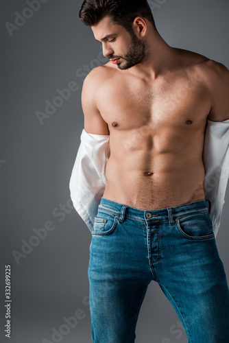 seductive muscular man in white shirt and jeans isolated on grey