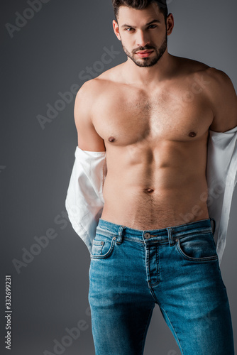 handsome sexy man in white shirt and jeans isolated on grey
