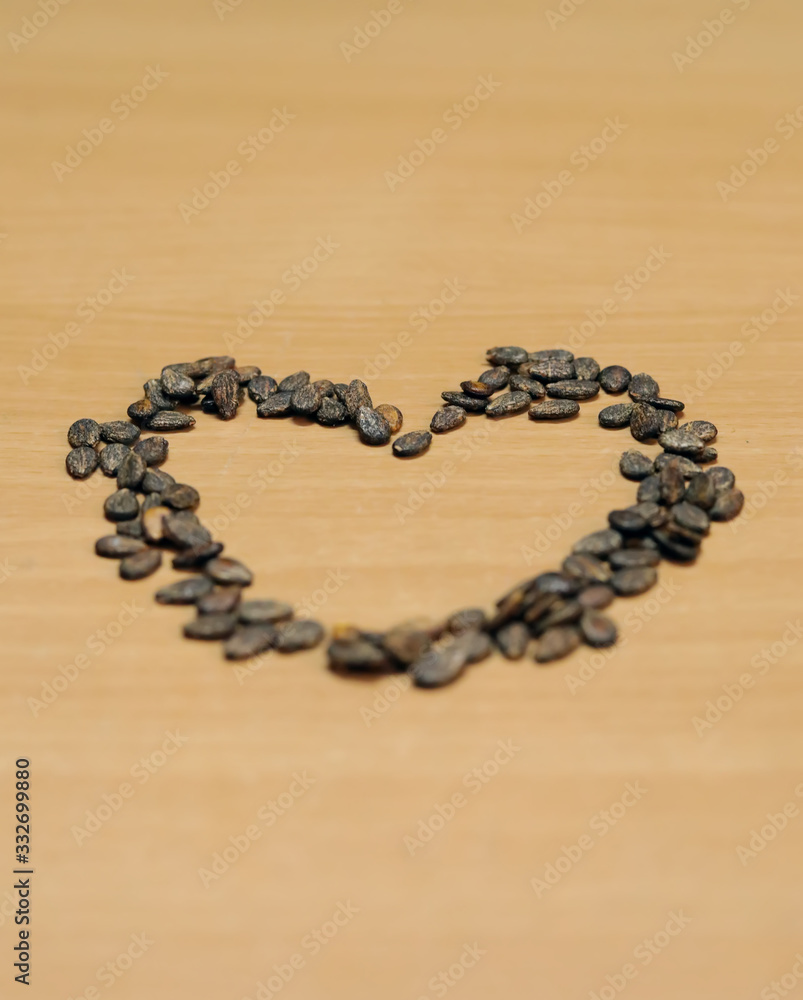 Heart shape made of watermelon seeds, composition isolated over the wooden table, Heart shape made of watermelon seeds, composition isolated over the wooden table,