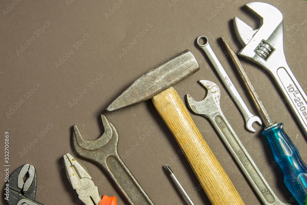 Construction tools on textured grunge paper consisting of pipe wrench, screwdriver, metal, hammer and free copy space on the top Construction tools on textured grunge paper consisting of pipe wrench, screwdriver, metal, hammer and free copy space on the top