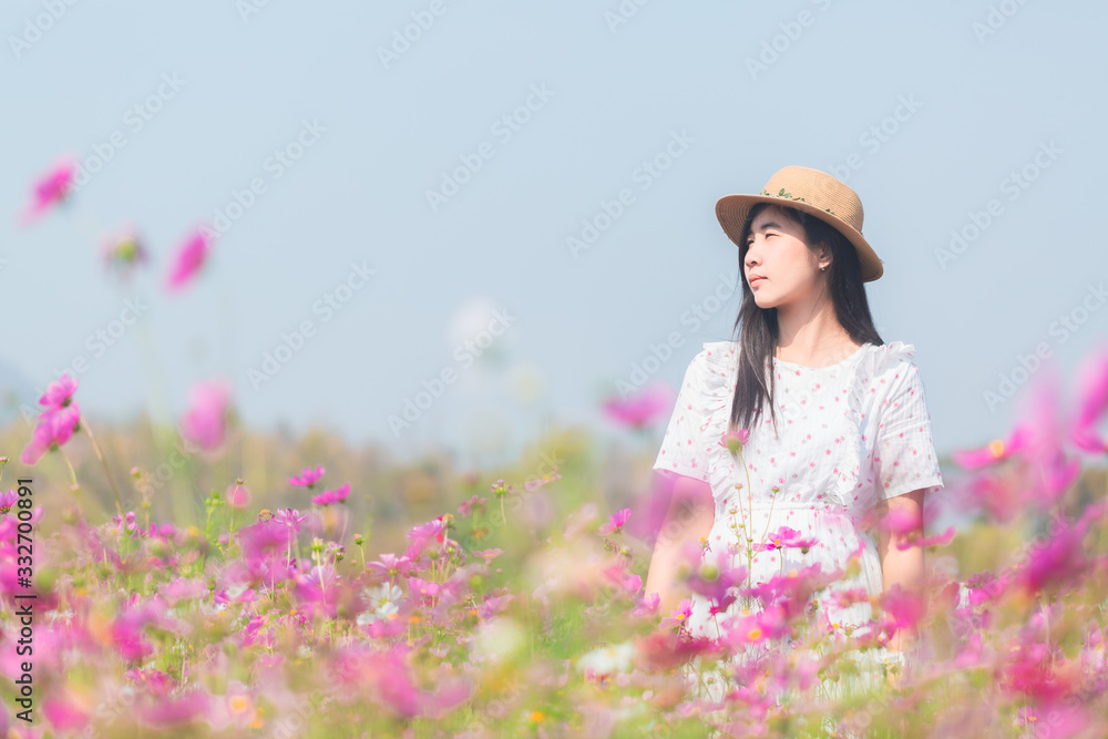 Panoramic view of young lady in white dress walking in the pink flower field meadow in the countryside with copy space for graphic design purpose