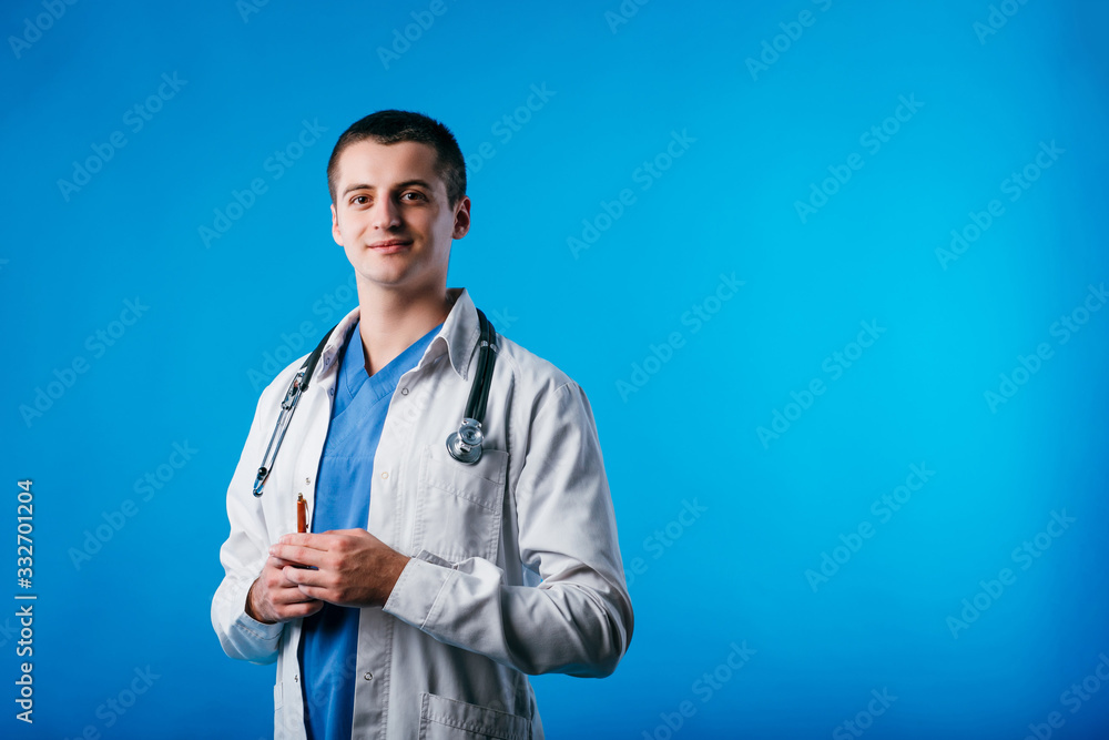 Portrait of young doctor with stethoscope holding pen isolated on blue background Portrait of young doctor with stethoscope holding pen isolated on blue background