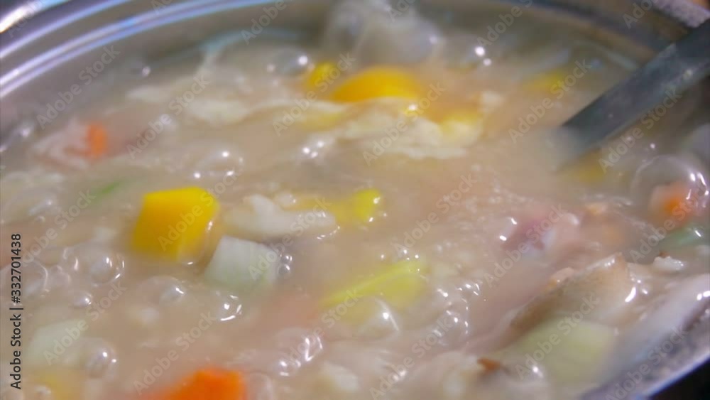 A spoon is mixing the boiling mushroom soup with vegetables and pearl barley A spoon is mixing the boiling mushroom soup with vegetables and pearl barley