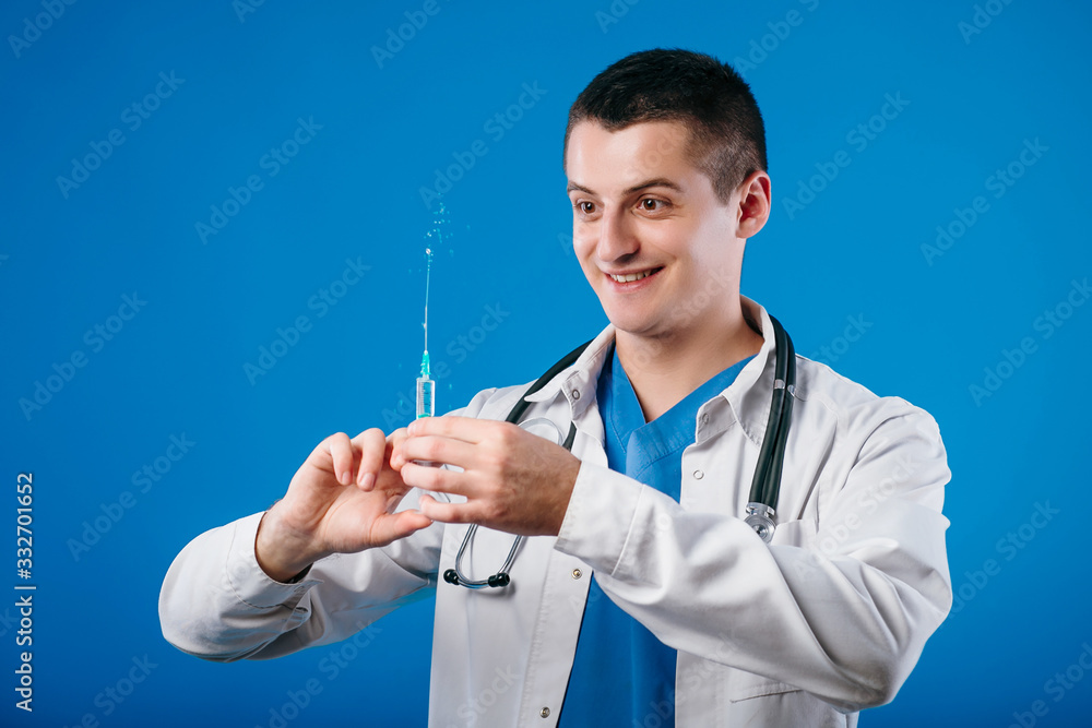 Portrait of funny emotional male doctor with syringe isolated on blue background Portrait of funny emotional male doctor with syringe isolated on blue background