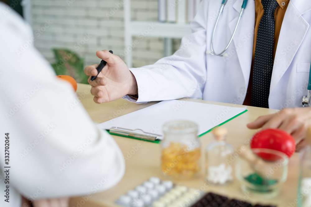 Asian specialist doctor talking to a patient in doctor office in hospital. Patient worried about his sickness and influenza come to a doctor and taking examination in hospital. Healthcare concept. Asian specialist doctor talking to a patient in doctor office in hospital. Patient worried about his sickness and influenza come to a doctor and taking examination in hospital. Healthcare concept.