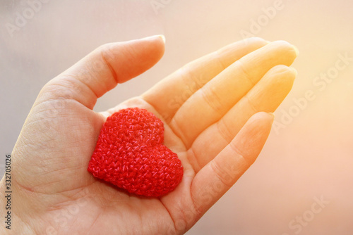 Knitted red heart in a female hand.