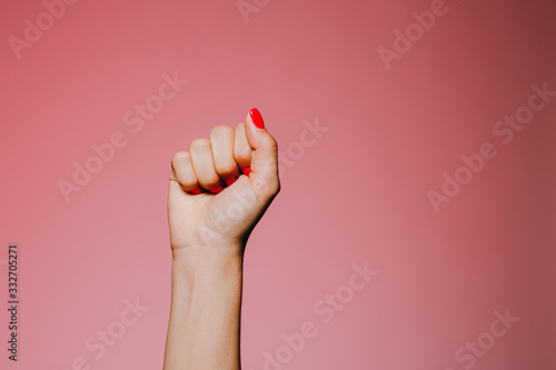 Woman's hands with bright manicure isolated on pink background fist stone gesture