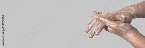 Foto Hands of a young guy in soapy foam on a gray background