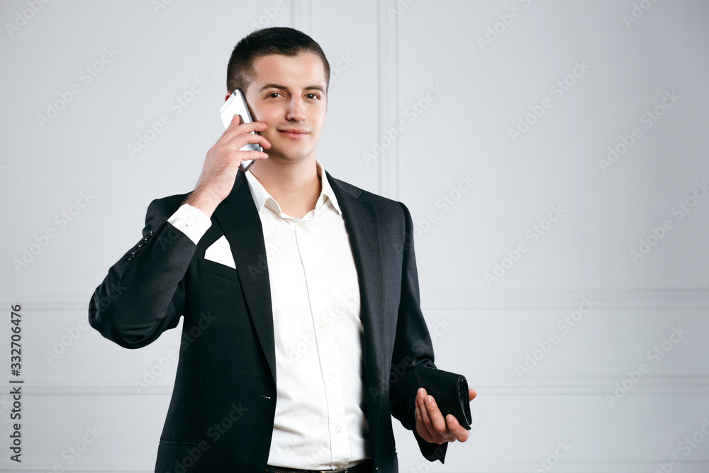 Portrait of a young businessman talking on the phone with a wallet in hand Portrait of a young businessman talking on the phone with a wallet in hand