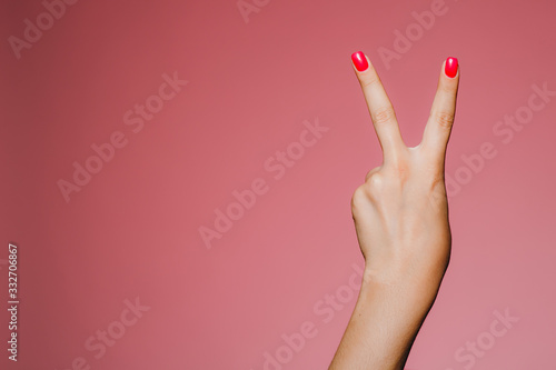Woman's hands with bright manicure isolated on pink background V letter