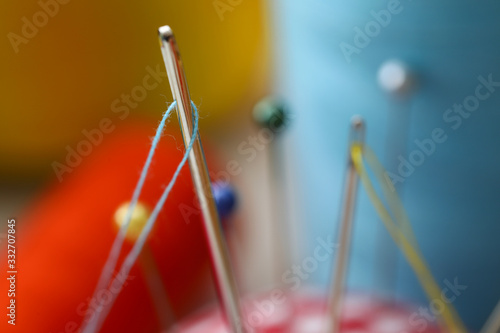 Needle eye with piece of blue thread stick out of pincushion photo