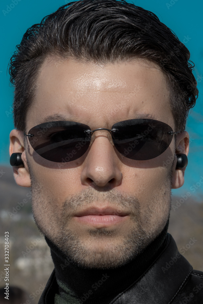 Portrait of a man with a smooth haircut and dark sunglasses looking ...